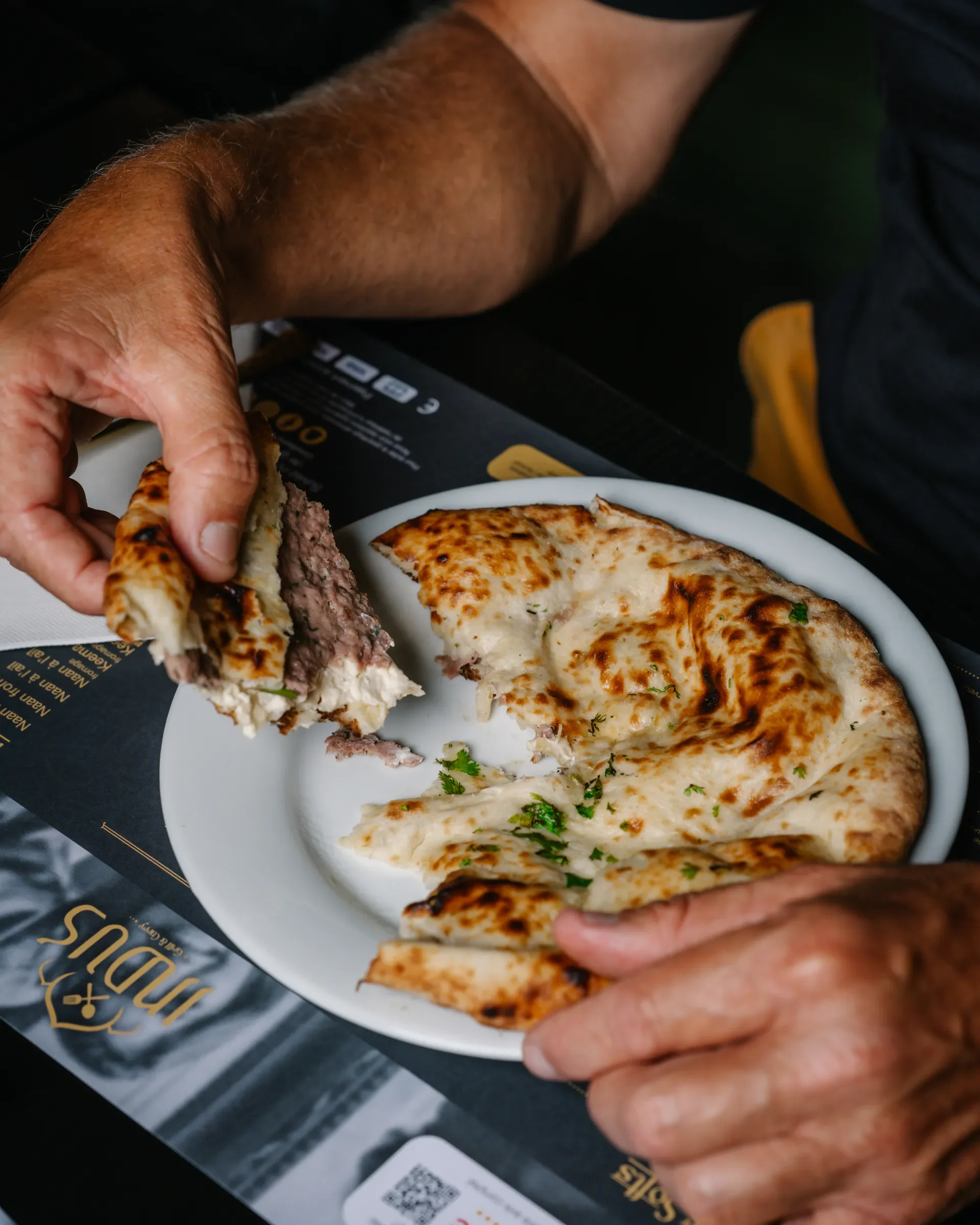 Un naan garni ouvert à la main chez INDUS